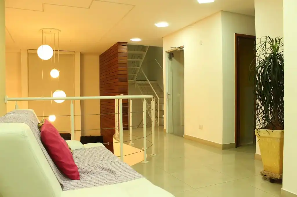 Recepção do Instituto do Bem Estar, com sofá, iluminação e acesso à escada